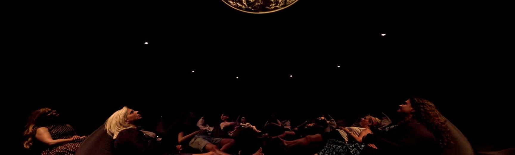 People lying down in a darkened room with light show above