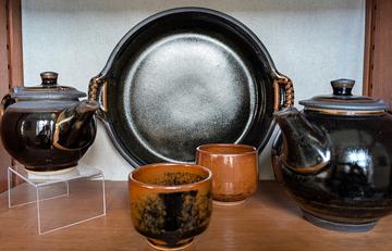 Bubier Two teapots and a plate in a dark glaze with two cups in the foreground