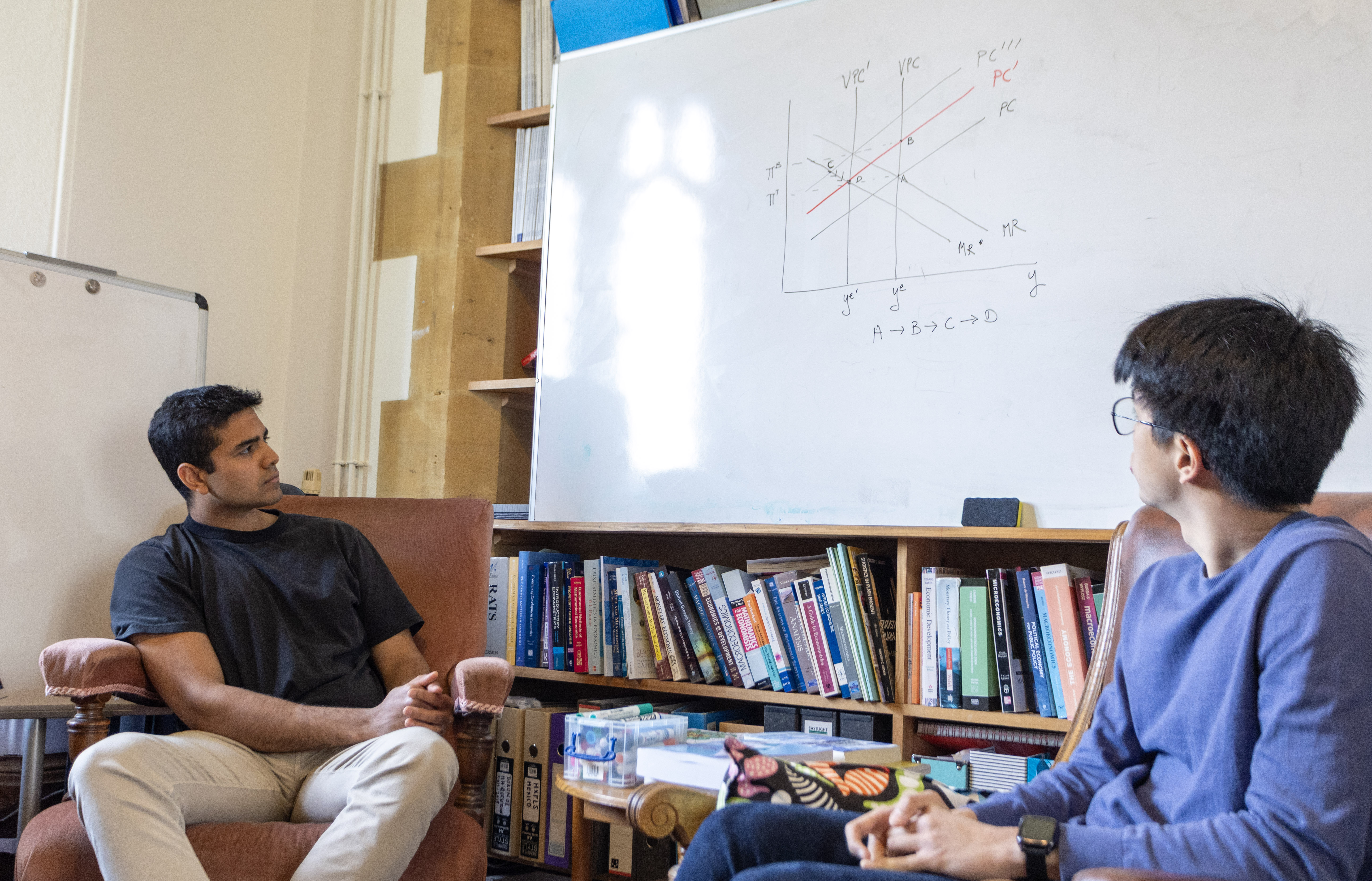 Two students in front of a whiteboard with a graph