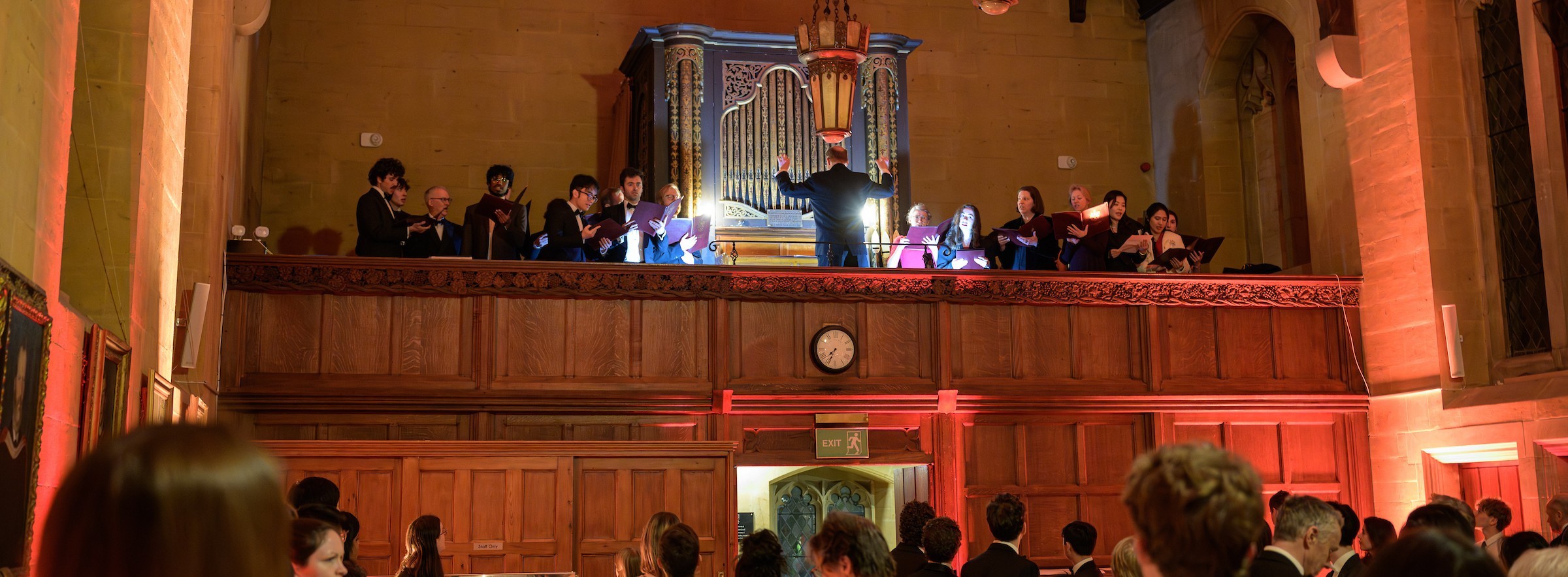 Choir singing from gallery in Arlosh Hall with organ in background