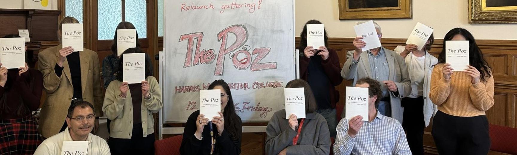 Contributors and supporters of 'The Poz' pose behind copies of the magazine, in recognition of contributors' anonymity