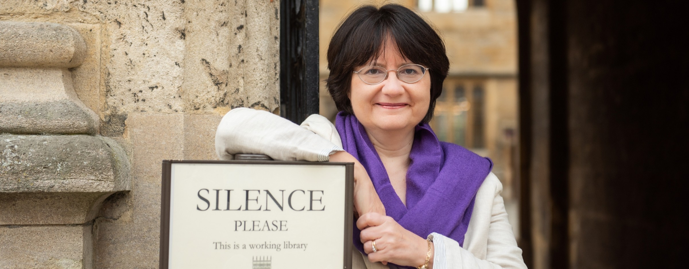 Kate McLoughlin next to library sign with words "Silence Please"