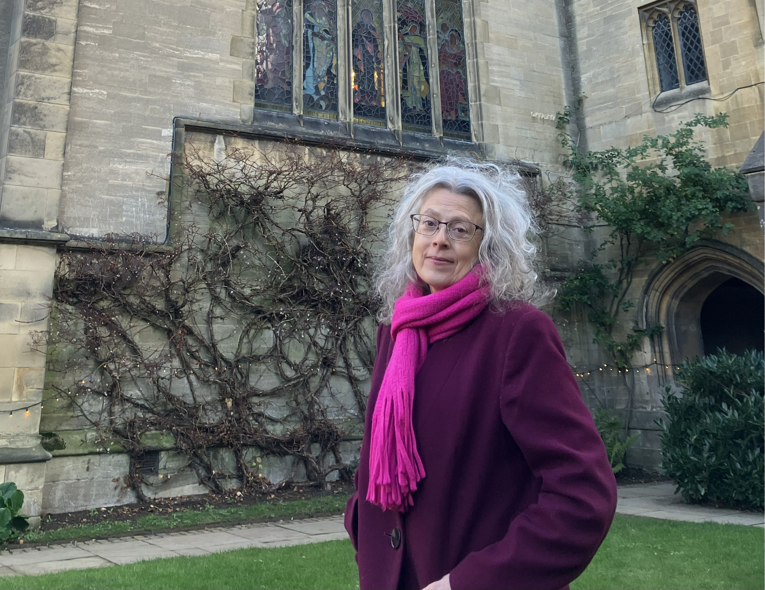 Woman in a coat standing in college quad in front of chapel