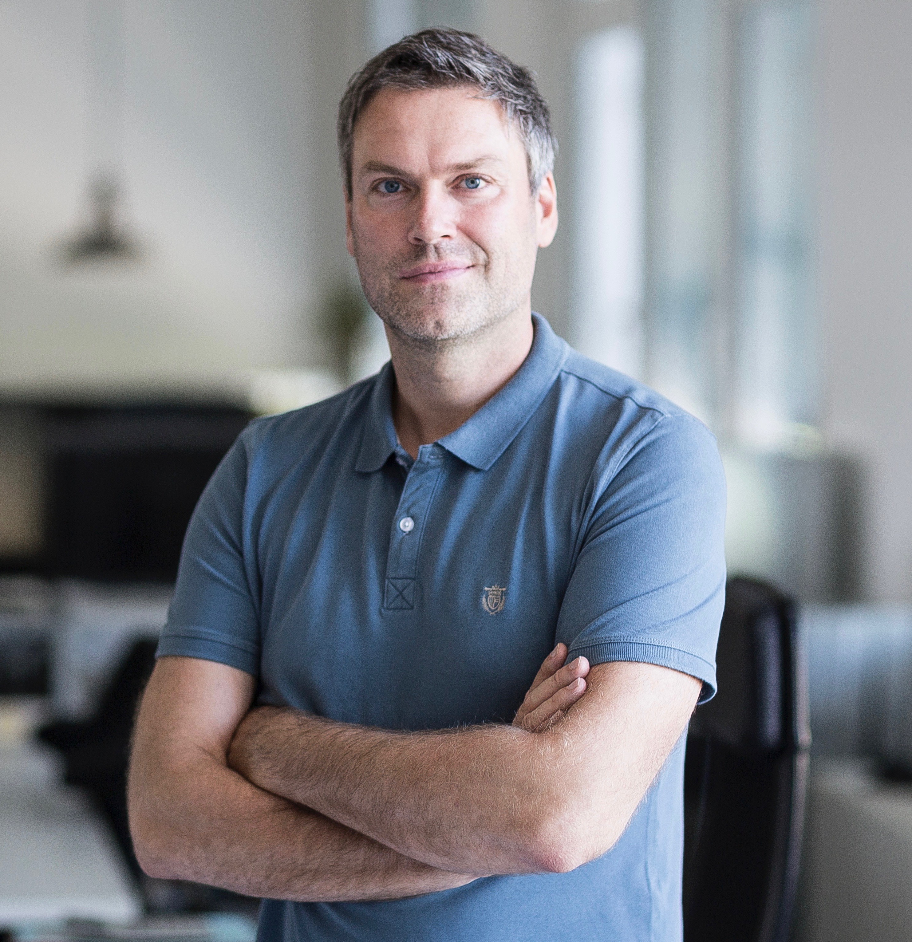 A man in a T-shirt standing with folded arms
