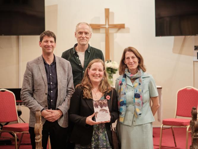 Two men and two women pose with one woman holding a book in her hand