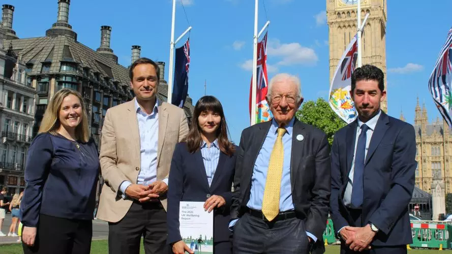 Five people in front of Big Ben with person in centre holding a report