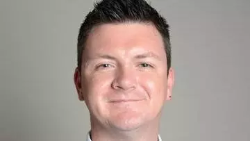 A man wearing a tie posing for a headshot.