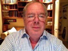 Headshot of a man with glasses in a checked shirt  