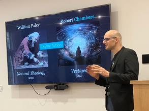 A student speaks in front of a screen depicting William Paley and Robert Chambers