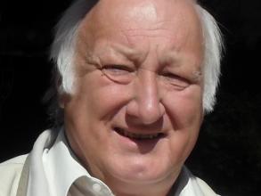 Alan Ruston posing in front of black background.