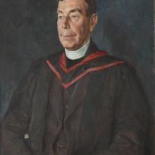A three quarters length portrait of a man in academic dress with a dog collar