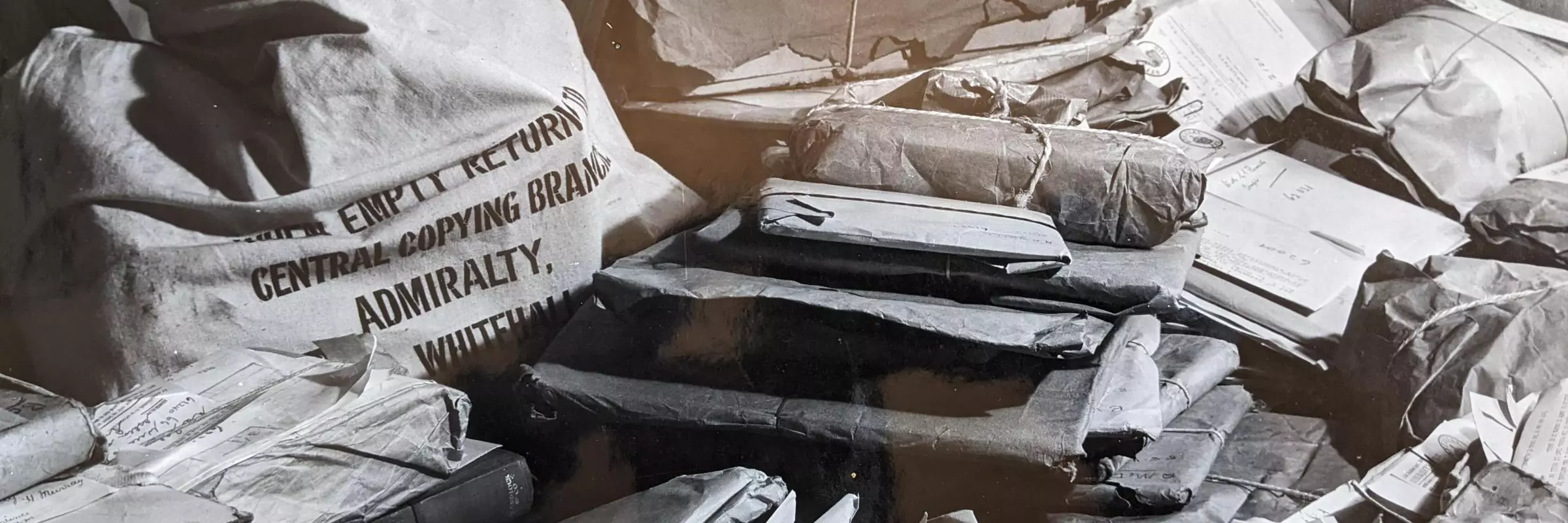 Black and white photograph of piles of parcels and bags containing letters all crowded together
