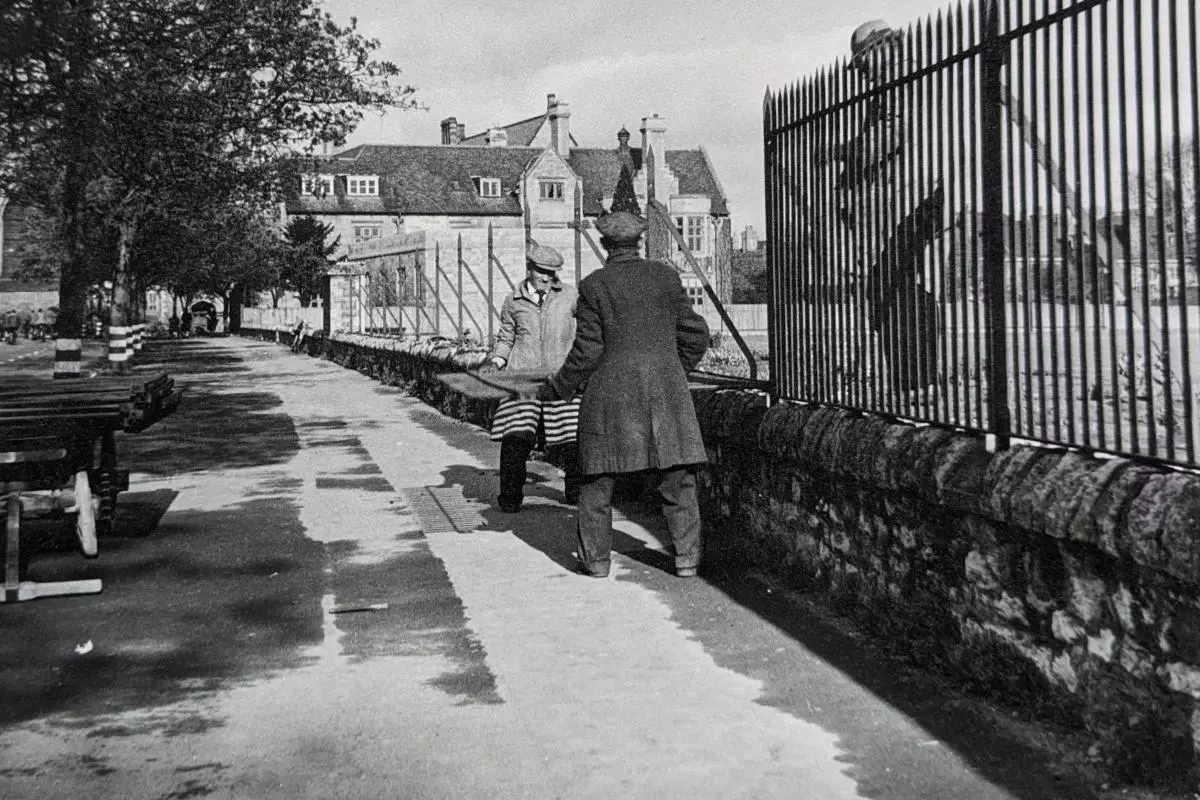 Two men moving a large metal railing from a wall